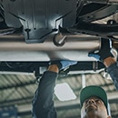 Technician Working on Vehicle Muffler Representing Exhaust Repair Parts Category